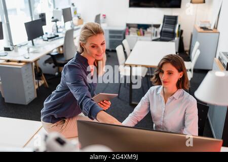Female professionals discussing over computer in office Stock Photo