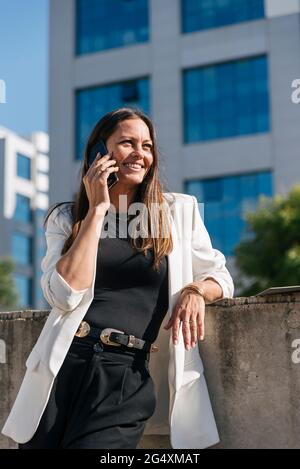 Female entrepreneur smiling while talking on mobile phone Stock Photo