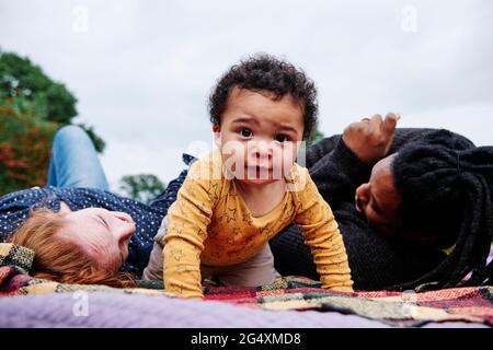 Carefree son crawling on picnic blanket at park Stock Photo