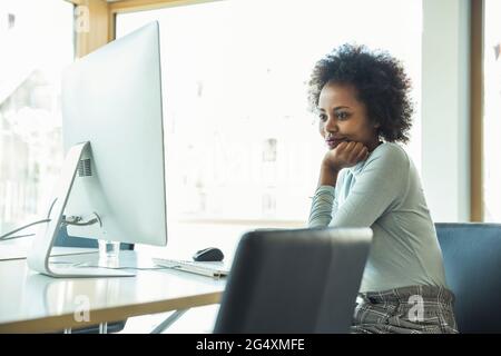 Female professional with hand on chin using computer on desk at office Stock Photo