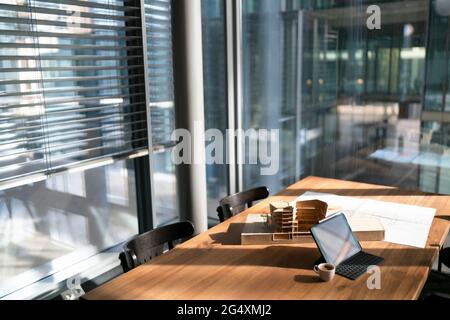 Architectural model with blueprint and laptop on table at office Stock Photo