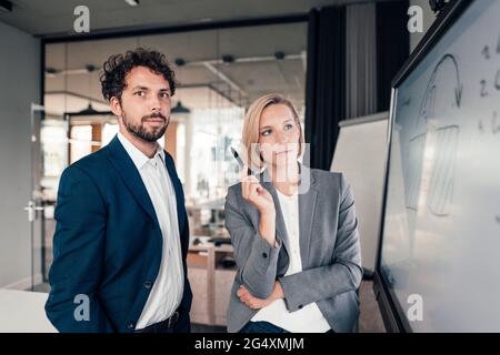 Mid adult partners standing by projection screen in office Stock Photo