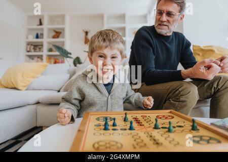 Son clenching teeth and fists while father sitting on sofa in background at home Stock Photo