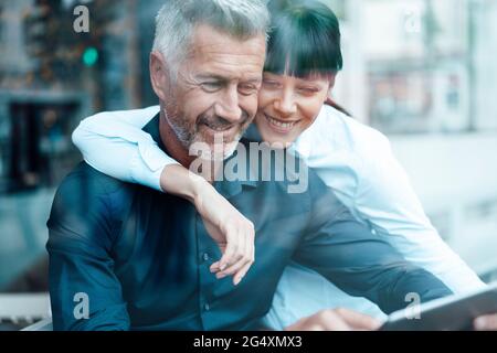 Business couple smiling while using digital tablet at coffee shop Stock Photo