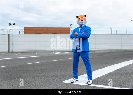 Man wearing vibrant blue suit and tiger mask posingÂ in empty parking lot Stock Photo