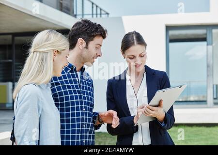 Couple and businesswoman using digital tablet by residential building Stock Photo