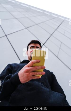 Man using smart phone by wall Stock Photo