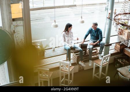 Team working together while sitting by window at cafe Stock Photo