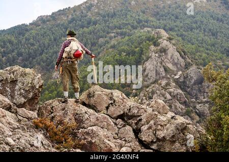 Mid adult male mountaineer looking at view while standing on mountain Stock Photo