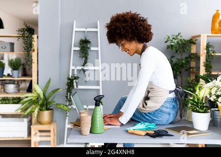 Female shop owner using laptop while sitting on table Stock Photo