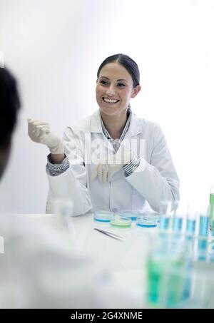 Smiling technician colleagues in front of machinery with robotic arm at ...