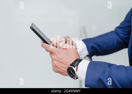 Businessman using mobile phone while leaning on railing Stock Photo