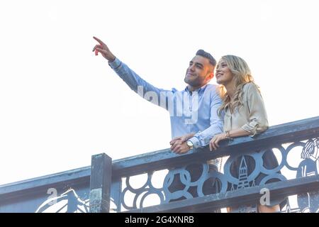 Man pointing while standing at railing with girlfriend Stock Photo