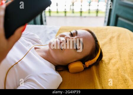 Relaxed woman using mobile phone on bed at home Stock Photo