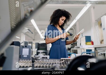 Businesswoman scanning bar code on book in industry