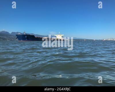 Freight ship cargo vessel at anchor in shore Stock Photo