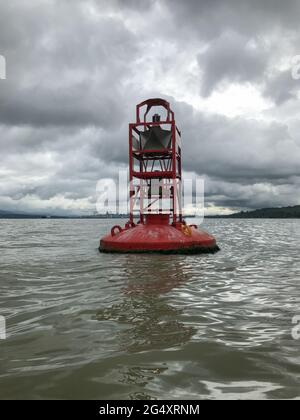 Red bell buoy shipping channel marker near shore in ocean Stock Photo