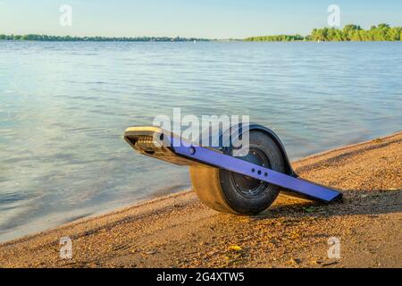 One-wheeled electric skateboard (personal transporter) on a lake shore in Colorado Stock Photo
