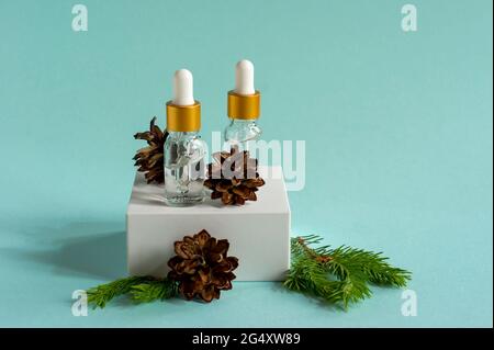 Cedar and spruce essential oil in small glass bottles on trendy podium on blue background Stock Photo