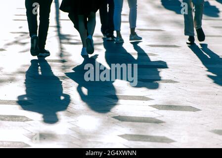 Shadows and silhouettes of people on a road during sunny evening.