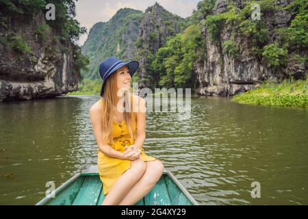 Woman tourist in boat on the lake Tam Coc, Ninh Binh, Viet nam. It's is UNESCO World Heritage Site, renowned for its boat cave tours. It's Halong Bay Stock Photo