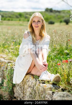 Portrait of beautiful young girl posing near field of wild flowers Stock Photo