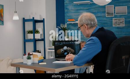 Senior remote man architect working on modern cad program analysing gears design. Industrial old engineer studying prototype idea on laptop computer showing cad software on device display Stock Photo