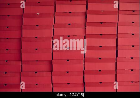 Background of lots of red cardboard boxes with footwear stacked at shoe factory warehouse Stock Photo
