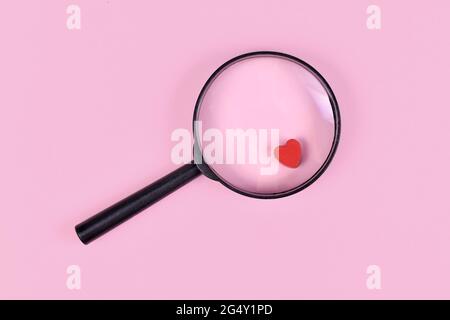 Concept for finding love with magnifier glass and red heart icon on pink background Stock Photo