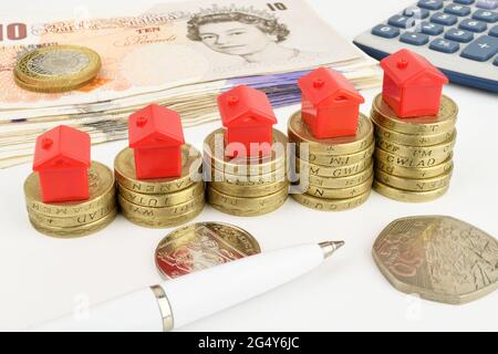 Rising stacks of coins with toy houses on top, to represent property finance. Stock Photo