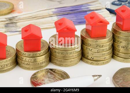 Rising stacks of coins with toy houses on top, to represent a rising property market. Stock Photo