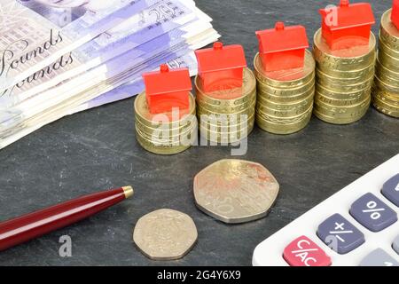 A still life with stacks of pound coins with toy houses on top. A metaphor on property finance. Stock Photo