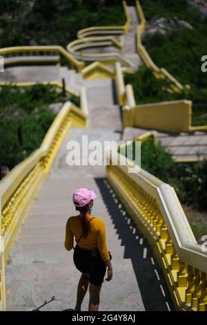 A young thai woman walks down over long staircase near Buddhists temple Stock Photo
