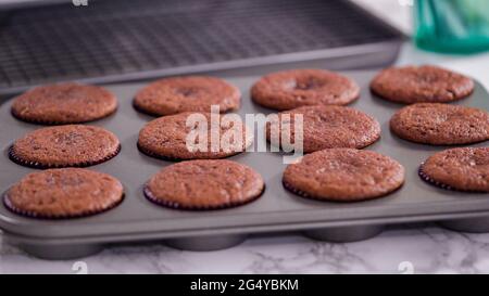Step by step. Cooling red velvet cupcakes on a kitchen drying rack. Stock Photo