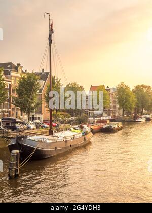 Constructed clock tower along canal in Amsterdam with evening light sky and reflection Stock Photo