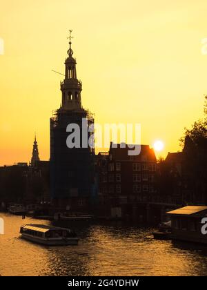 Silhouette technique of clock tower along canal in Amsterdam under golden light sky in evening Stock Photo