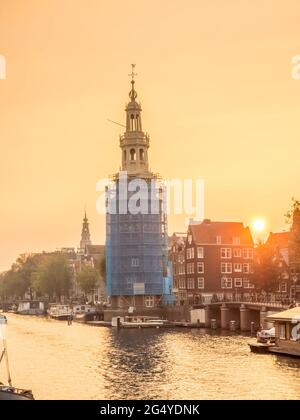 Constructed clock tower along canal in Amsterdam with evening light sky and reflection Stock Photo