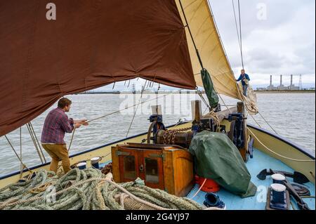 Mate Pat Fox and skipper Ed Gransden (left) stowing away the staysail on 'Edith May' historic sailing barge in Thames estuary, Kent, England. Stock Photo