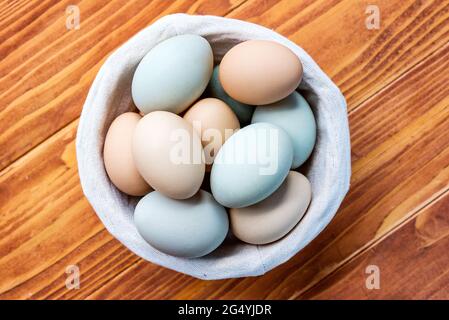 Fresh Chicken and duck eggs collect from farm products natural in a wicker basket on a wooden table. Healthy eating concept - Top View Stock Photo