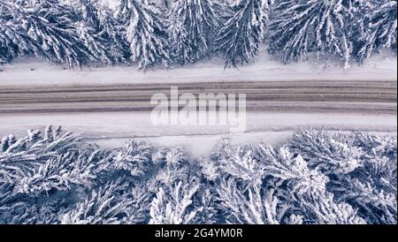 Snowy mountain road and forest, drone view. Stock Photo