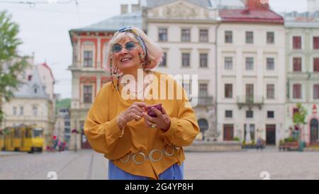 Elderly stylish tourist woman looking for way find route using smartphone in old town Lviv, Ukraine Stock Photo