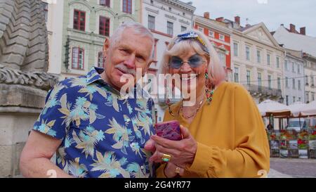 Senior stylish couple tourists man, woman, grandmother, grandfather looking for way using smartphone Stock Photo