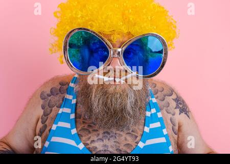 Fat serious man with beard and wig smokes cigarettes Stock Photo