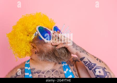 Fat man with beard and wig smokes cigarettes Stock Photo