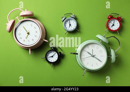 Different multicolor alarm clocks on green background Stock Photo