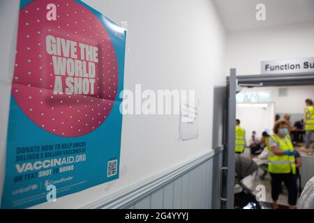 London, UK, 24 June 2021: inside a vaccine centre in Tooting a poster appeals to people to donate to Vaccinaid to supply more vaccines to poorer countries. Anna Watson/Alamy Live News Stock Photo