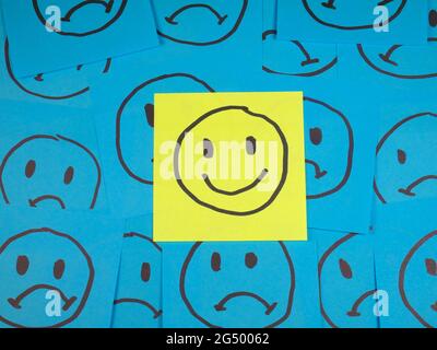 Positive smiley face on sticky note over sad faces Stock Photo