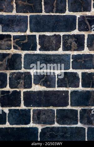 Dark, black Weathered brick wall made from reclaimed bricks. Black brick wall Stock Photo