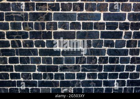 Dark, black Weathered brick wall made from reclaimed bricks. Black brick wall Stock Photo
