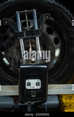 Close-up of a tire clamped by a leveler that passes the automatic alignment of the wheels in the garage, garage and tools for the mechanic. Stock Photo